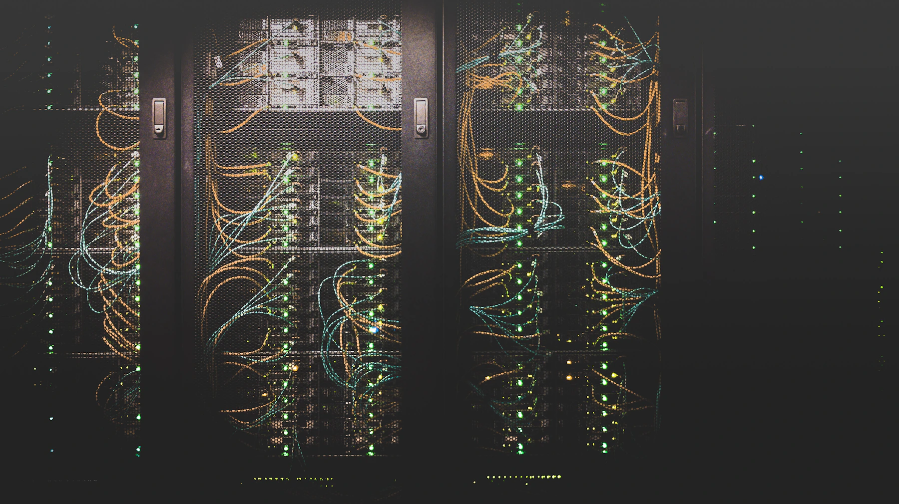 Dark data centre corridor lined with networking cables